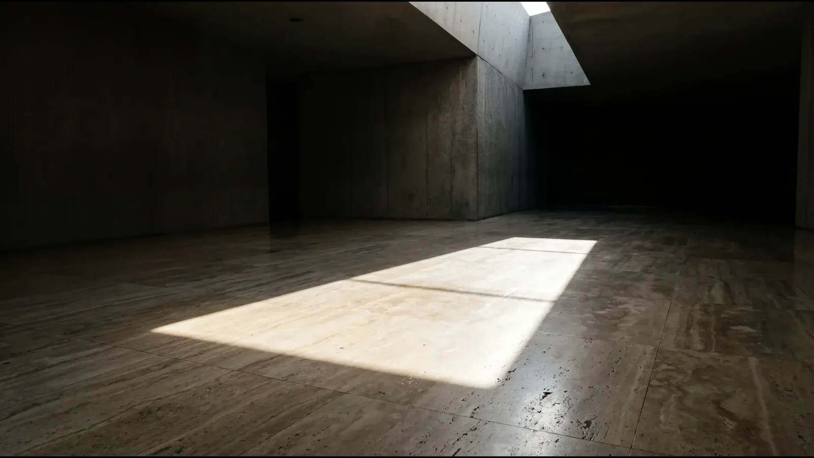 An empty concrete room with one rectangle of daylight on the floor, and nobody in it.
